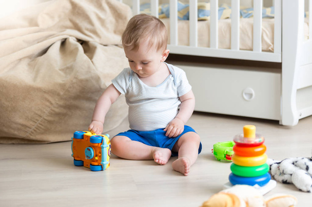 Baby boy playing on floor with colorful toy car - Fotoğraf, Görsel