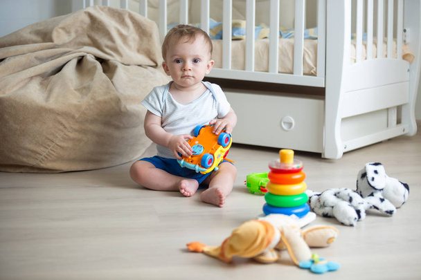 Happy baby boy playing with toys on floor at bedroom - Foto, immagini