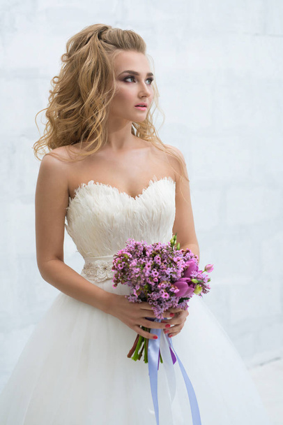 Gorgeous young bride with nice bouquet in studio - Фото, зображення