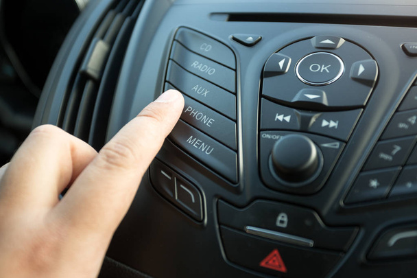 Κοντινό πλάνο γυναικεία δάχτυλο πατώντας το κουμπί radio pa ελέγχου αυτοκινήτων - Φωτογραφία, εικόνα