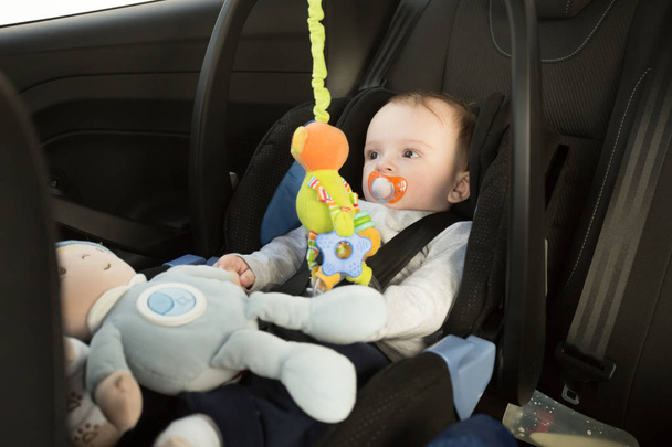 Chlapeček sedí v autosedačce a hraní s hračkami - Fotografie, Obrázek
