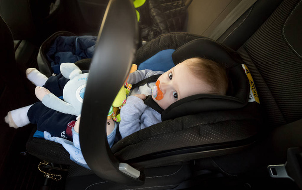 Lindo niño sentado en el asiento de seguridad del bebé en el coche
 - Foto, imagen