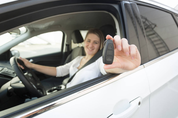 Крупный план женщины-водителя, показывающей ключи через открытое окно автомобиля
 - Фото, изображение