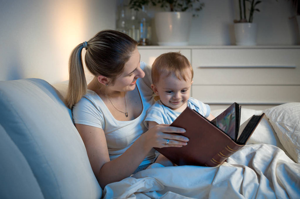 Bela mãe sorridente lendo história para seu menino antes de ir
 - Foto, Imagem