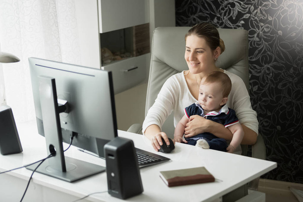 Madre con su hijo en la oficina usando la computadora
 - Foto, Imagen