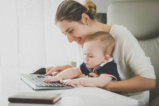 Sorrindo empresária posando com seu bebê no escritório
 - Foto, Imagem