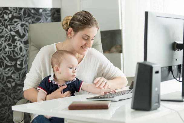 赤ちゃんにコンピューターを使用する方法を教える女性の肖像 - 写真・画像