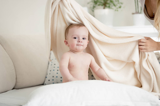 Moeder die haar babyjongen in grote witte deken op bed - Foto, afbeelding