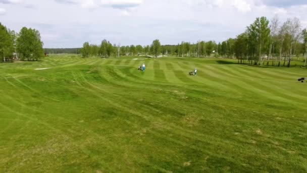 Letecký pohled na golfové hřiště. Golfisté kráčí plavební dráhy na kurzu s golfový bag a vozík - Záběry, video