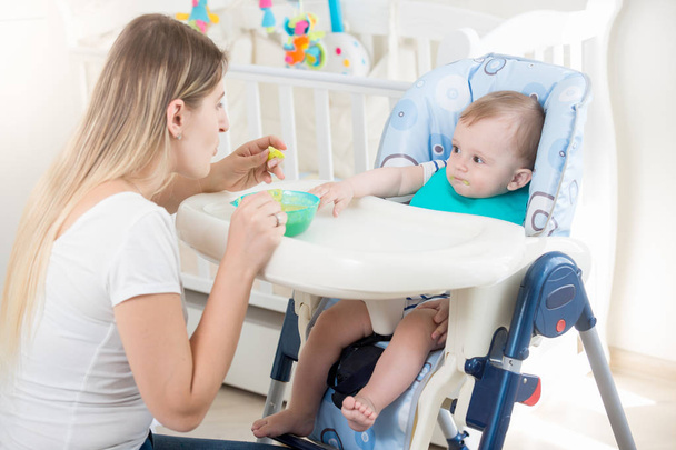 Anya etetése a baba etetőszék a nappali - Fotó, kép