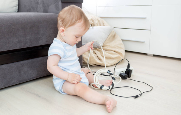 Baby boy pulling cables from electrical extension - Foto, Imagen