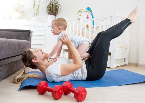 Happy mother doing yoga with her baby boy on floor at living roo - Photo, Image