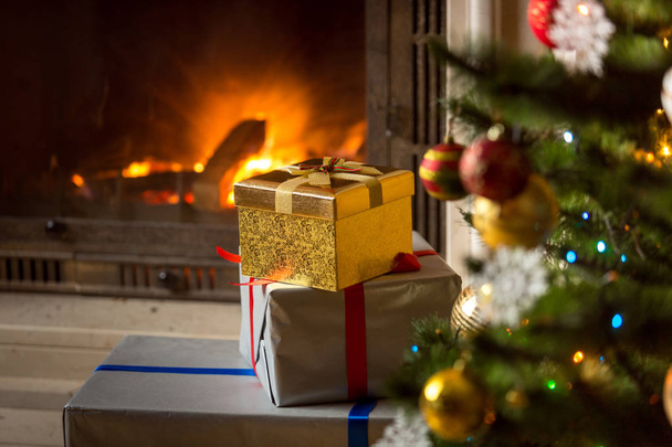Hoge stapel Kerstcadeaus met brandende open haard - Foto, afbeelding