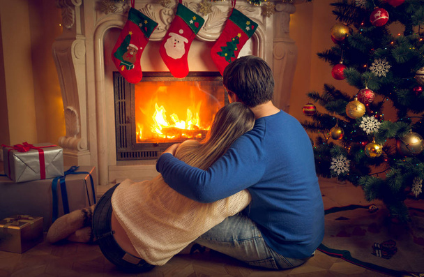 Rear view image of couple relaxing by the fireplace - Photo, Image