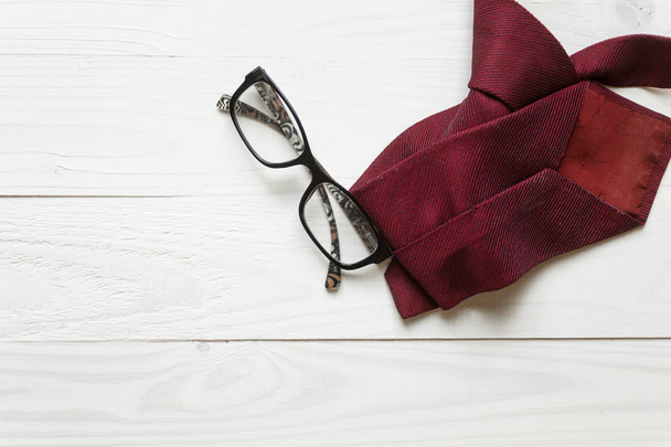 Corbata masculina y anteojos acostados sobre fondo de madera blanca
 - Foto, imagen