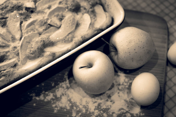 getönte Nahaufnahme Bild von hausgemachten Kuchen und Äpfeln auf Holzbrett - Foto, Bild