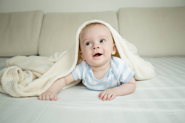 幸せな小さな赤ちゃん毛布の下のベッドの上でクロール - 写真・画像