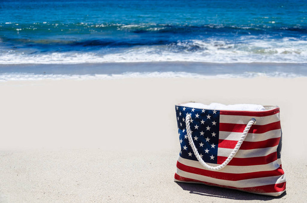 Пляжная сумка с американским флагом цвета около океана
 - Фото, изображение