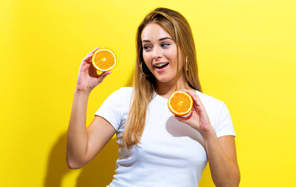 Happy young woman holding oranges halves - Photo, Image