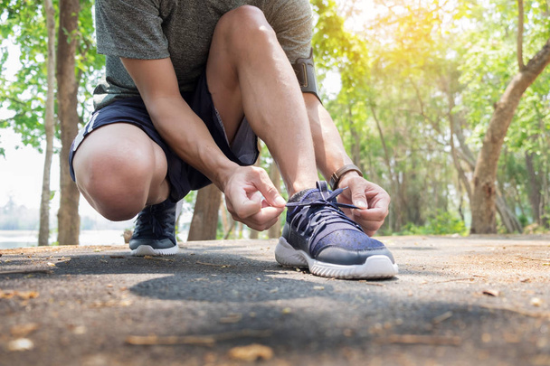 Обрізаний знімок молодого чоловіка бігуна, що затягує взуттєві шнурки
,  - Фото, зображення