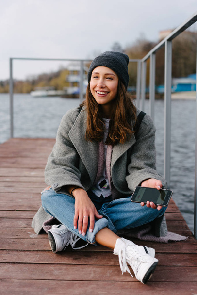 Young pretty girl on wooden bench on old pier - Фото, зображення