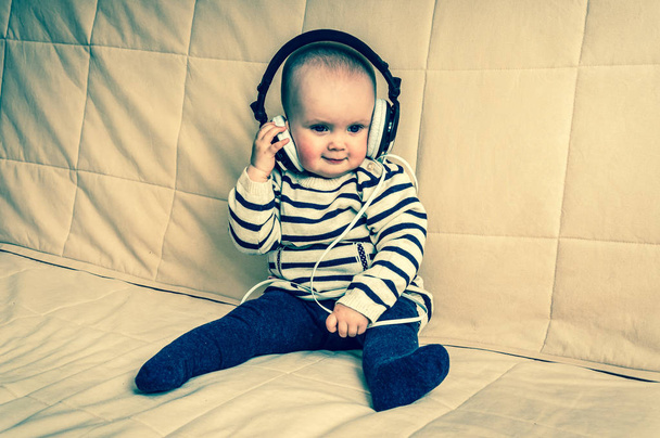 Χαριτωμένο μωρό με ακουστικά ακούει μουσική στο σπίτι - Φωτογραφία, εικόνα