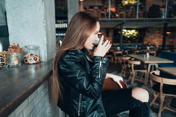 Beautiful girl in a black jacket in a cafe - Fotó, kép