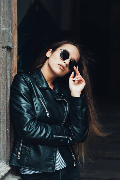 Menina bonita em uma jaqueta preta e óculos de sol
 - Foto, Imagem