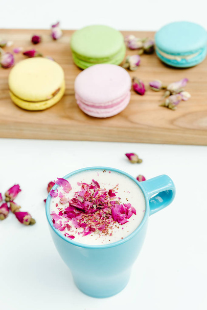 View on morning french macarons and a blue cappuccino cup with rose petals  - Photo, Image