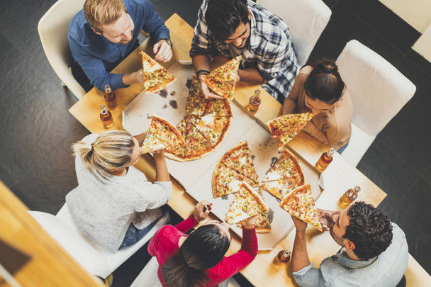 Молоді люди їдять піцу і п'ють сидр
 - Фото, зображення