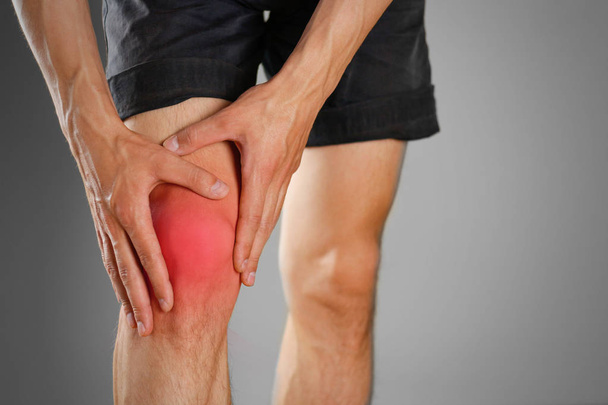 The guy clings to a bad knee. The pain in his leg. Closeup. The  - Foto, Imagen