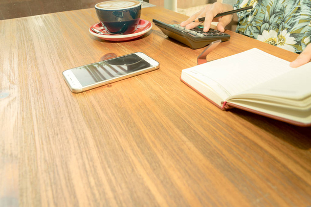 kobiet biznesu jest obliczania wydatków na drewnianym stole z kawą gorące mocha - Zdjęcie, obraz