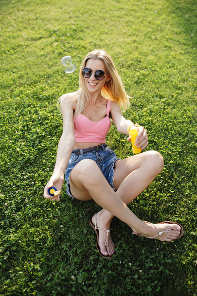 Pretty woman blowing bubbles in summer park - Fotografie, Obrázek