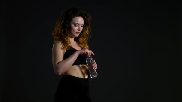 athletic girl drinks from a bottle water, woman in the gym enjoying fresh water, thirsty woman after sport, portrait brunette drinking mineral water, healthy living, water balance in the body - Video