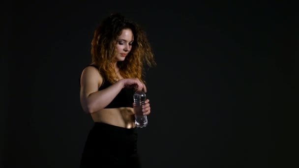athletic girl drinks from a bottle water, woman in the gym enjoying fresh water, thirsty woman after sport, portrait brunette drinking mineral water, healthy living, water balance in the body - Záběry, video