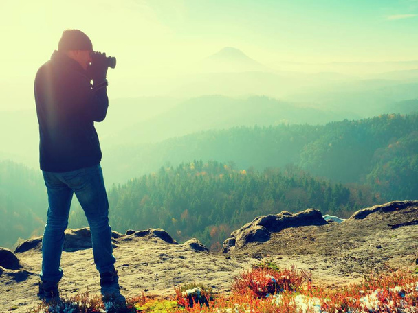 Fotograaf op klif. Natuurfotograaf neemt foto's met spiegel camera op peak - Foto, afbeelding