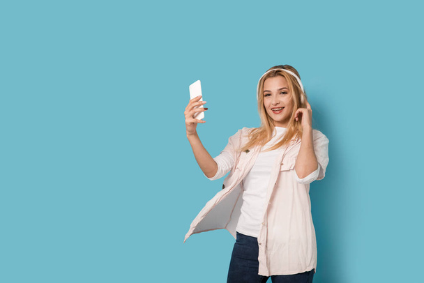 Cheerful blonde girl with smartphone smiling and listening - Foto, immagini