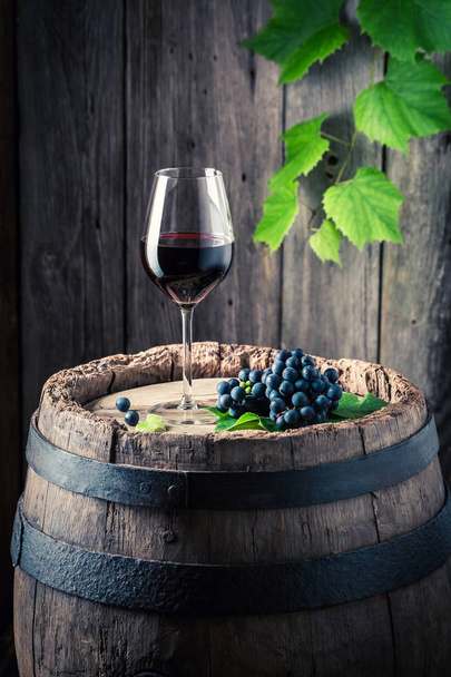 Kieliszek czerwonego wina i świeżych winogron na starej beczki - Zdjęcie, obraz