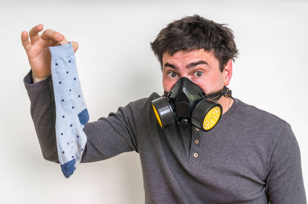 Homme avec masque à gaz tient sale chaussette puante
 - Photo, image