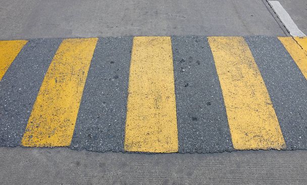 A yellow speed bump for slowing traffic - Фото, изображение