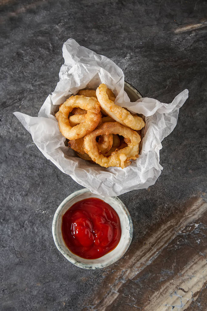Seafood. Squid rings fried in mesle with lemon and ketchup on a  - 写真・画像