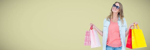 Shopper smiling with bags against light green background - 写真・画像