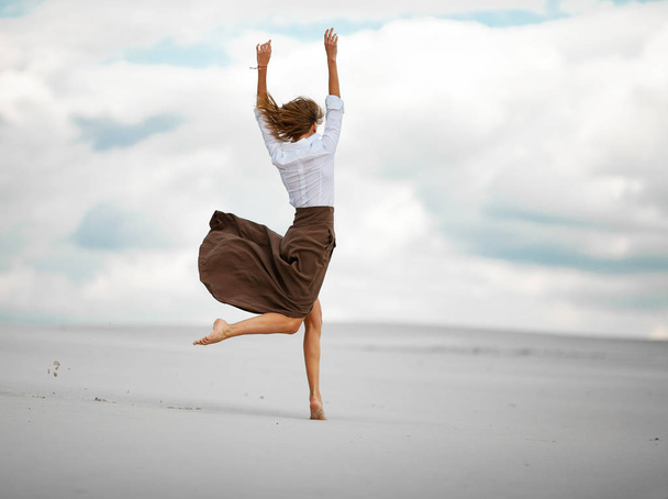 junge Frau springt in Wüste auf Sand. - Foto, Bild