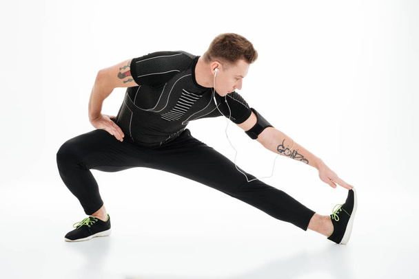 Retrato de um belo desportista fazendo exercícios de alongamento antes de correr
 - Foto, Imagem