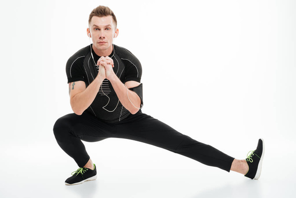 Portrait of a handsome sportsman doing stretching exercises before jogging - Foto, afbeelding