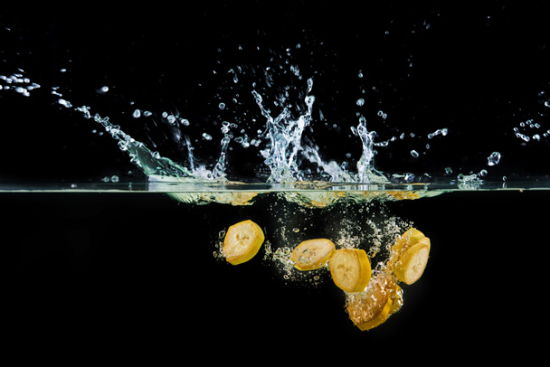 pieces of banana falling into water with splashes - Zdjęcie, obraz