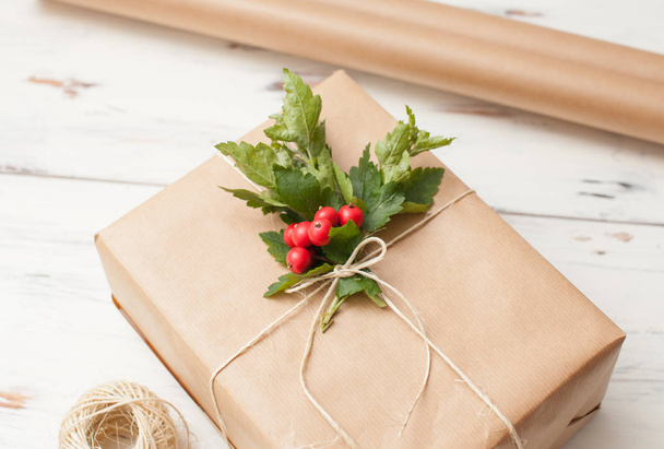 Packed for gift giving in a simple paper with twig and red berries - Foto, Imagem