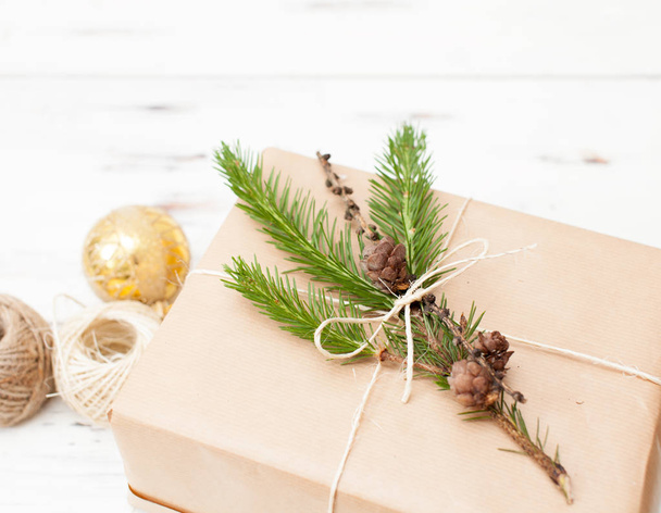 Wrapped gift in plain paper with a fur-tree branch and Christmas balls - 写真・画像