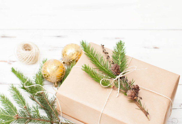 Wrapped gift in plain paper with a fur-tree branch and Christmas balls - Fotoğraf, Görsel