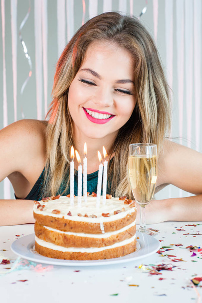 Pretty girl looking at lit candles on birthday cake for celebrat - Фото, изображение